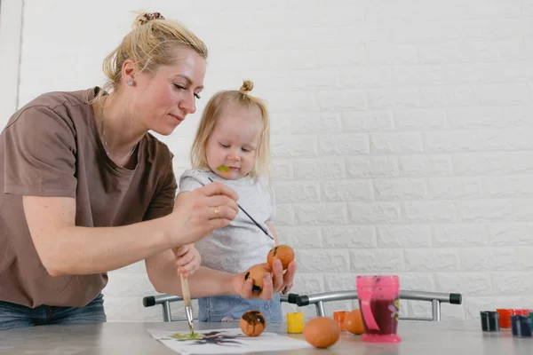 kids learn to color eggs for Easter together with their mom at home in the kitchen