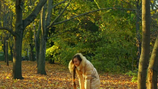 Giovane ragazza divertirsi lanciando foglie gialle . — Video Stock
