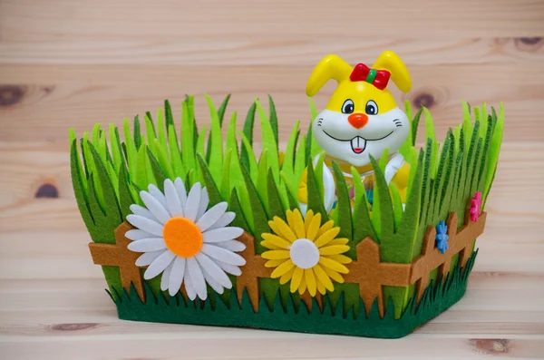 Счастливый съедобный кролик в гнезде с травой и цветами на деревянном фоне — стоковое фото