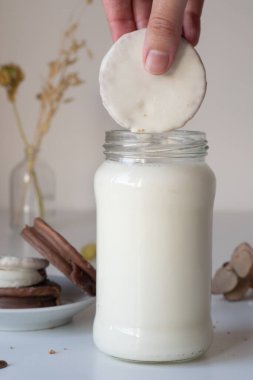 Mojando un alfajor blanco de çikolata, en un vaso con leche
