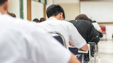 Görüntü okulunun arka planı. Üniversite öğrencileri sınav sorularına cevap yazıyorlar.