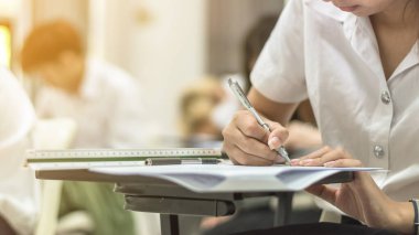 Okul ya da üniversite öğrencisi not alıyor ya da eğitim ve okur yazarlık konsepti için sınıfta sınav oluyor