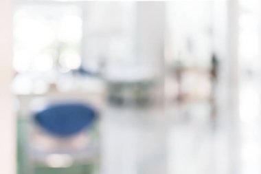 Arka plan bulanık. Boş ofis lobisine, giriş kapılarına ve cam perde duvarına bakıyor. 