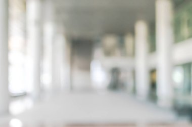 Arka plan bulanık. Boş ofis lobisine, giriş kapılarına ve cam perde duvarına bakıyor. 