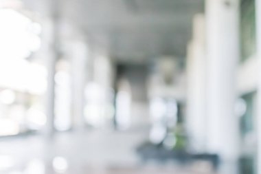 Arka plan bulanık. Boş ofis lobisine, giriş kapılarına ve cam perde duvarına bakıyor. 
