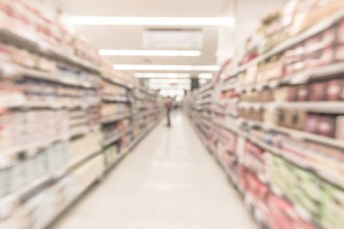 Bulanık süpermarket arka planında raflar yiyecek ürünleri ve alışveriş için günlük malzemeler var.