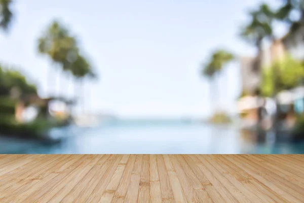 Wood floor with blur summer background tropical resort hotel with swimming pool water and palm tree