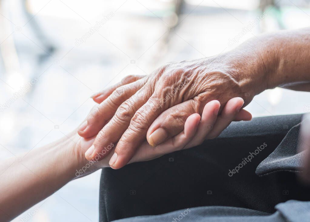 Disability awareness day and aging society concept with Parkinson disease patient or elderly senior person in support of nursing family caregiver's hand 