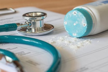 Doktorun not defterine steteskopla birlikte pudra döken talk pudrası ürünü: Üzerinde talk pudrası olan hastanın sağlık muayenesi belgesi