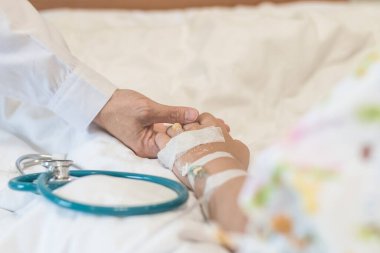 Çocuk hasta yatağında çocuk bakıcı konsepti ile pediyatrik doktor el desteği ile tıbbi hastane arka planında (ele odaklanın)