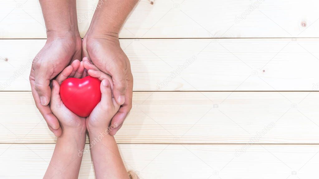 Parent supporting child's hands with red heart for I love you dad and Father's Day holiday celebration concept