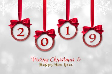 2019 Mutlu Noeller, kırmızı kurdele ve pırıl pırıl pırıl balo balosu Noel süsü ile mutlu yıllar. Gümüş beyazı kar tanecikleri beyaz kış arka planında asılı duruyor.