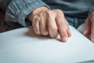Körler alfabesi kitabı görme engelli, düşük görüşlü, kör bir insanın el / parmak dokunuşlu kağıt dokusu işareti okuyor.