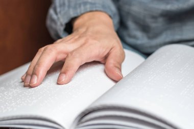 Körler alfabesi kitabı görme engelli, düşük görüşlü, kör bir insanın el / parmak dokunuşlu kağıt dokusu işareti okuyor.