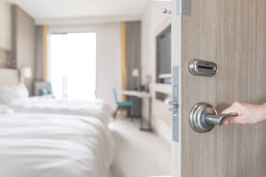 Otel odasının kapısı, misafir odasının iç manzarasına açılıyor. Modern konfor yatağının bulanık arka planına sahip. Gezgin için lüks, kaliteli yaşam alanı.