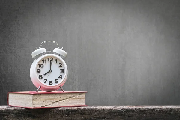 Back to school education concept with clock on book on black chalkboard