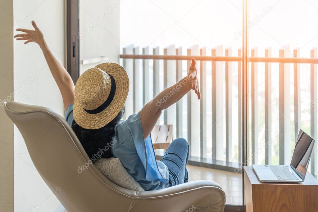 Life balance and summer holiday vacation concept with happy woman taking a break, celebrating successful work done, casually resting in luxury resort hotel workplace with computer pc laptop on desk