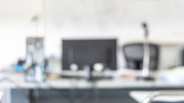 Bilgisayarlı kişisel masaüstü masası olan bulanık ofis çalışma alanı, cam pencere ve duvar kenarındaki beyaz odada bulanık çalışma masası iç alanı