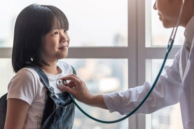 Mutlu çocuk hastası ve çocuk doktoru olan pediatrik bakım klinikte steteskopla çocuk kalp sağlığı ve sağlık hizmetleri konseptini inceleyen çocuk doktoru. 