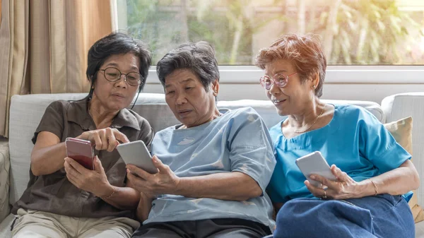 Aging society concept with Asian elderly senior adult women sisters using mobile digital smart phone application technology for social media network among friends community via internet communication