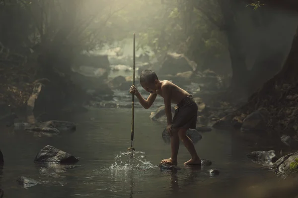 Fisher çocuk avcı creek ormanda.