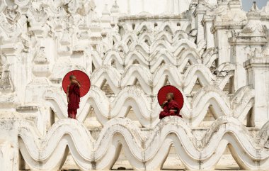 Burma, pagoda üzerinde kırmızı şemsiye tutan acemi keşiş