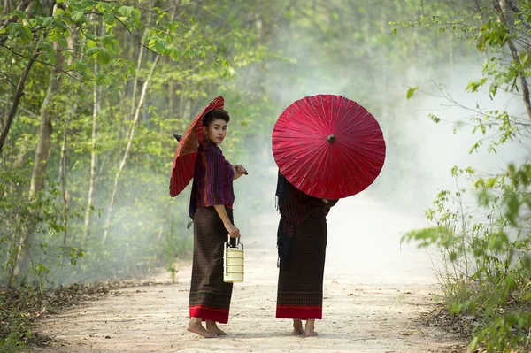 Dos mujeres caminando sosteniendo paraguas rojo — Foto de Stock