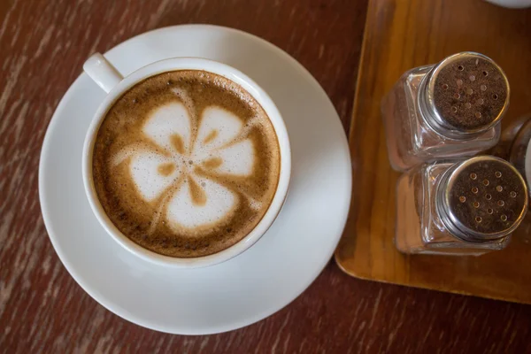 Een kopje koffie met hartje patroon in een witte beker — Stockfoto