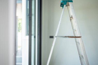 Modern bir oturma odasında duran gösterişli bir merdiven, sürmekte olan evi yenilemeyi ve DIY ruhunu simgeliyor..