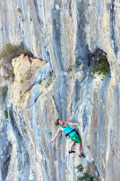Joven escaladora asaltando pared rocosa vertical — Foto de Stock