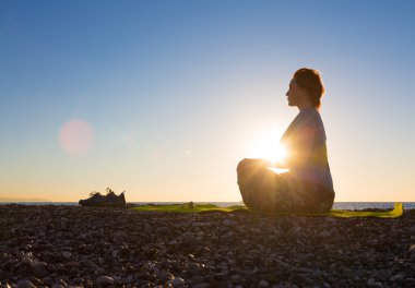Genç kadının yoga egzersiz tropik sahilde güneş doğarken yapması