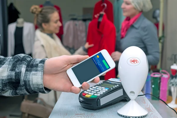 Near Field Communication - Man completing mobile Payment Woman shopping