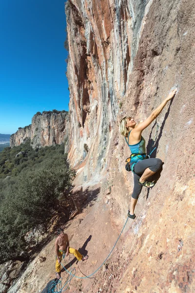 Kvinnliga extrema klättrare trappa upp på hög vertikal klippa — Stockfoto