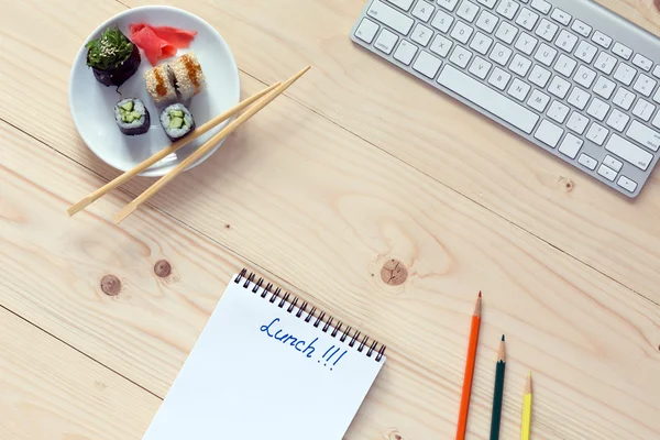 Sushi Set och ätpinnar dator och anteckningar på trä skrivbord — Stockfoto