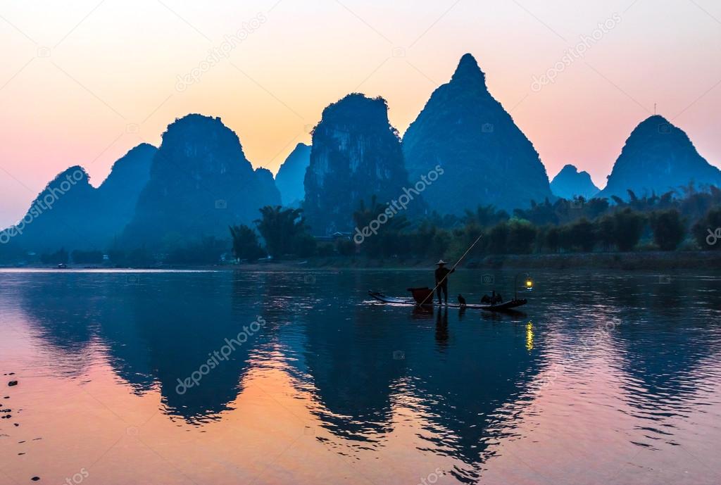 Silhouette of Fisherman with Cormorant Bird on Boat China River