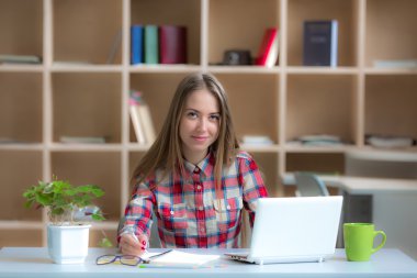 Young female Freelancer Professional working at desk in warm interior