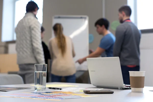 Mensen die werkzaam zijn op het Flip-overbord zakelijke items op tafel — Stockfoto