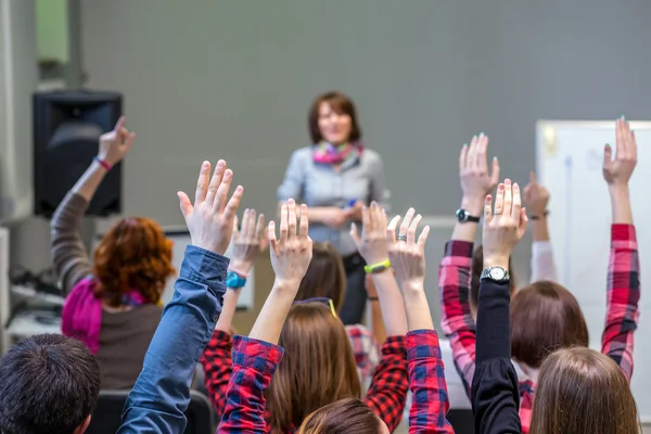 Alunos ativos levantando os braços prontos para responder a pergunta dos professores — Fotografia de Stock