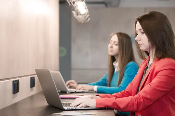Zwei junge Frauen arbeiten an Computern an der Theke — Stockfoto
