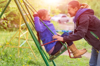 Genç anne küçük kızı Bahar park tahterevalli sürme