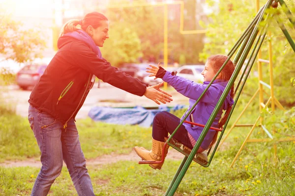 Jovem mãe cavalgando pequena filha no Seesaw em Spring Park — Fotografia de Stock