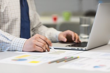 İşadamı laptop ve basılı grafikler üzerinde çalışma