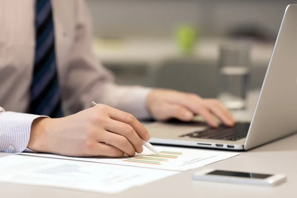 Empresario trabajando en Laptop y gráficos impresos — Foto de Stock