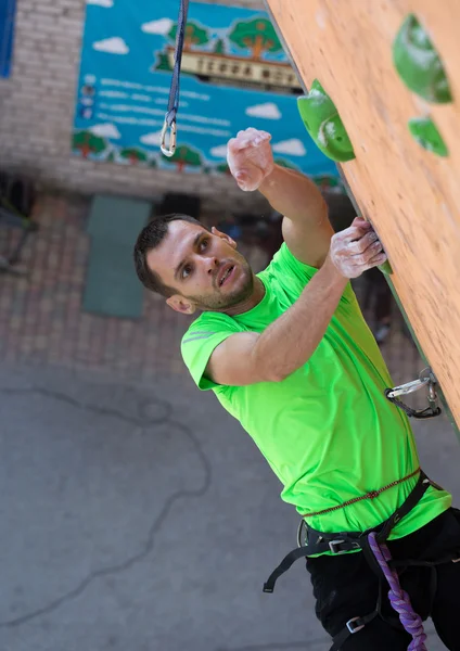 Альпініст, намагаючись досягти провести по скелелазіння стіна — стокове фото