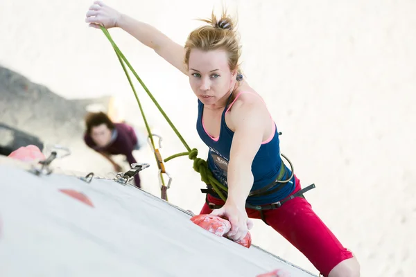 Linda atleta femenina colgando en la escalada de pared sosteniendo la cuerda — Foto de Stock