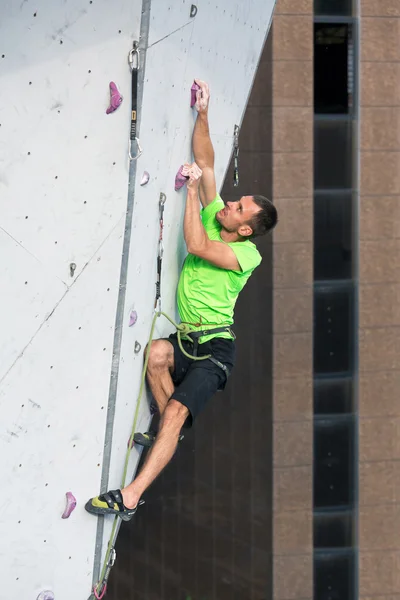 Escalador tentando alcançar um porão na parede de escalada — Fotografia de Stock