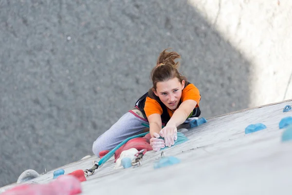 Junior lekkoatletka sprawia, że trudne ruch na ścianie wspinaczkowej — Zdjęcie stockowe