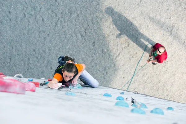 Junior kvinnlig idrottare på klättervägg och belaying domaren — Stockfoto