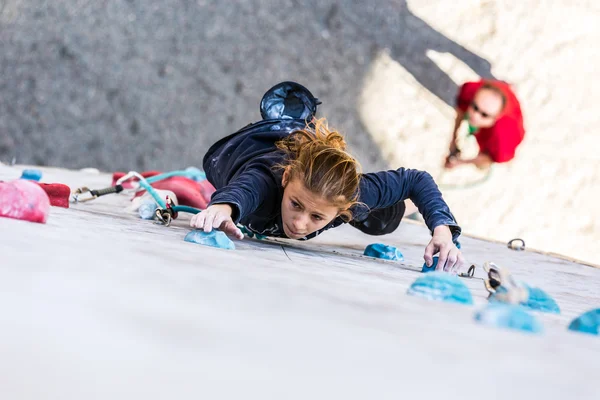 Junior kvinnlig idrottare på klättervägg och belaying domaren — Stockfoto