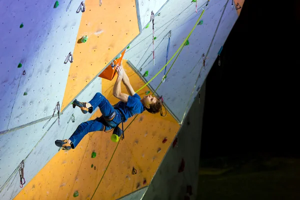 Escalador colgando en la pared de escalada — Foto de Stock